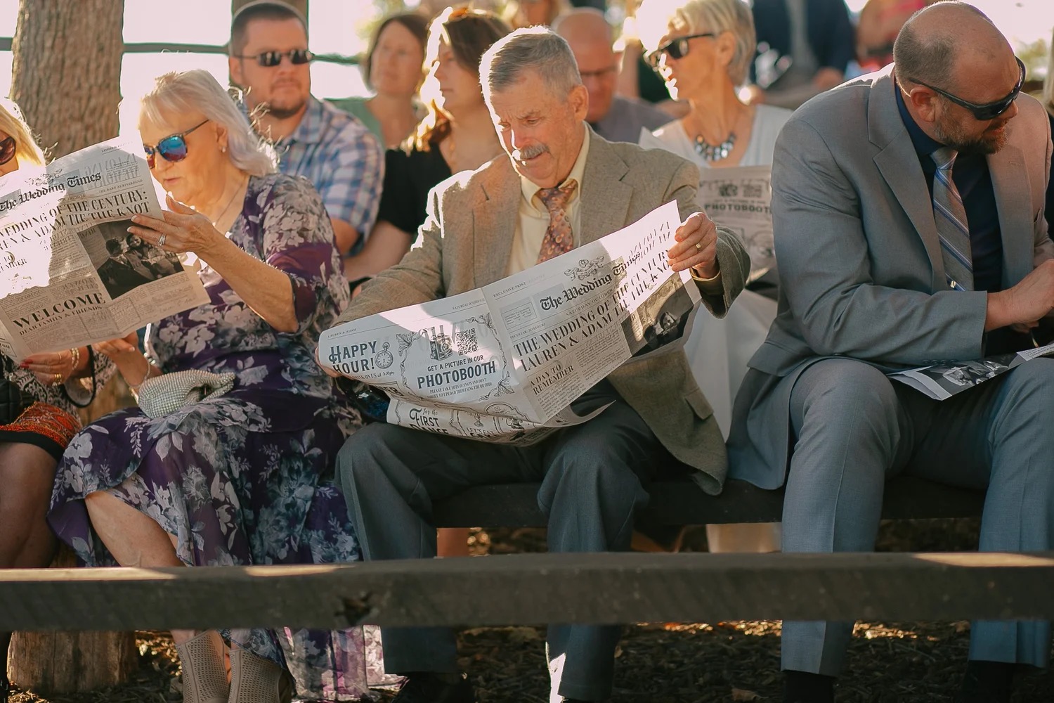 Wedding guests reading custom newspapers during Lauren and Adam's ceremony