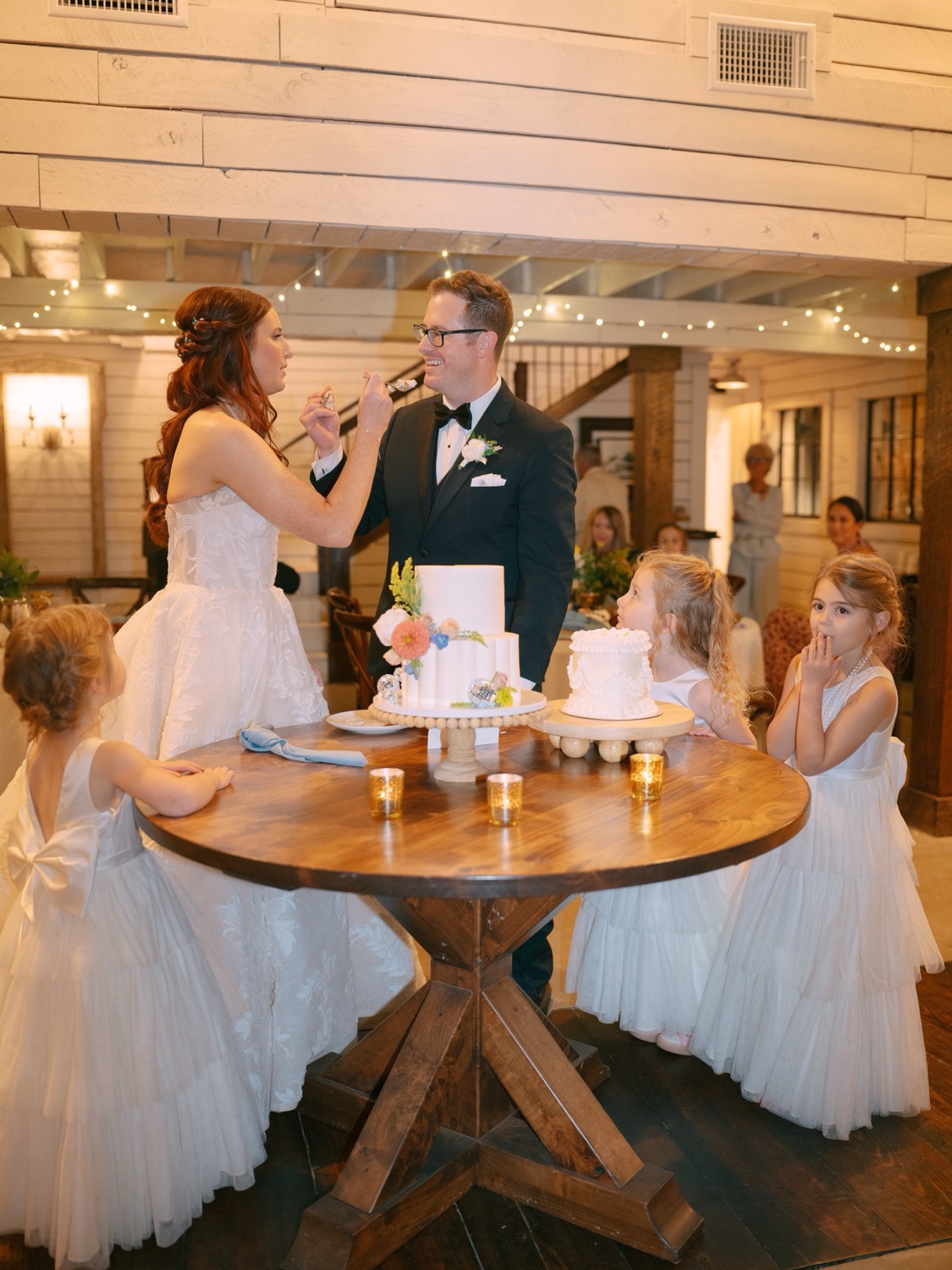 Lauren and Adam cutting wedding cake with children at The Barn at Riverbend