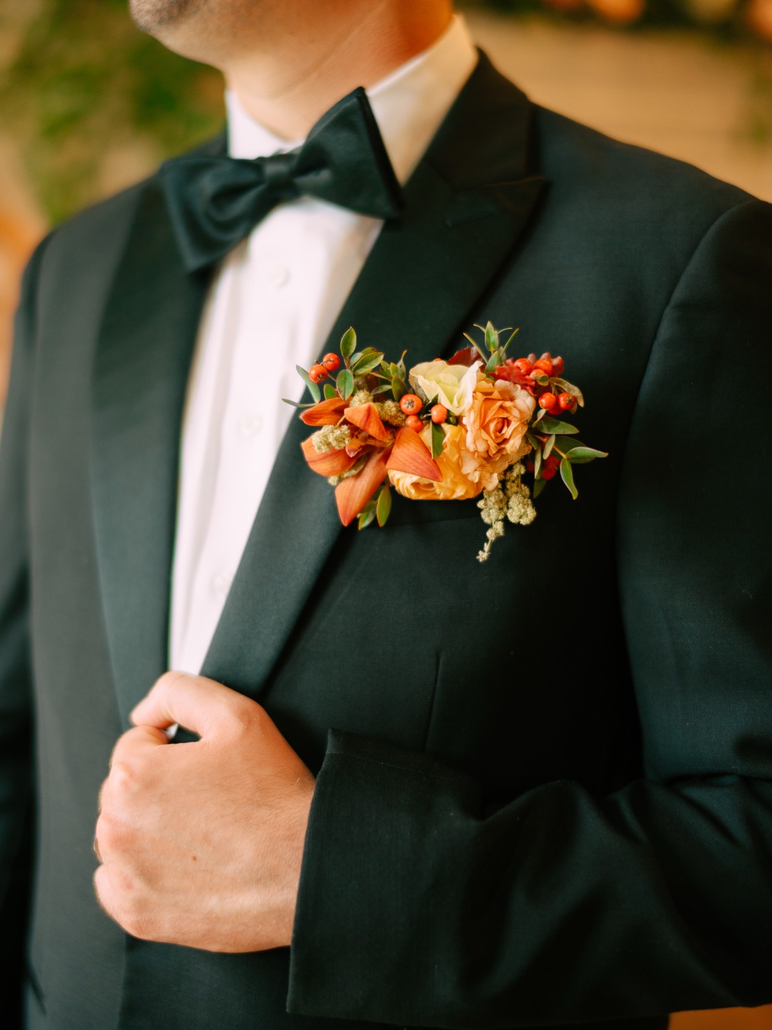 Logan's black tuxedo with an orange floral boutonniere