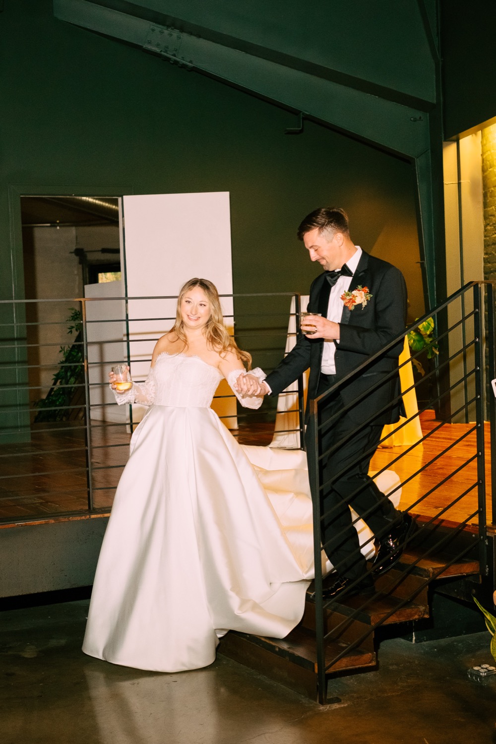 Lauren and Logan walking down a staircase after their wedding reception